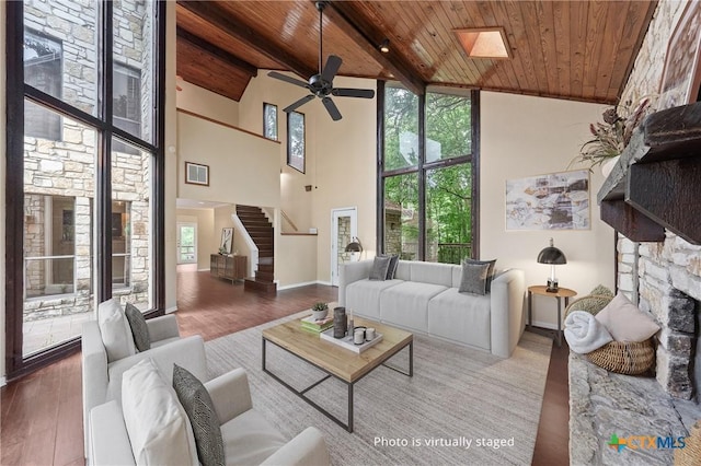 living room with a skylight, wooden ceiling, a high ceiling, and wood-type flooring