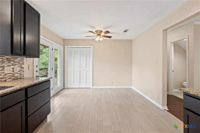 kitchen with ceiling fan, light stone counters, light hardwood / wood-style flooring, and tasteful backsplash