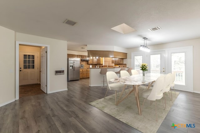 dining space featuring dark wood-type flooring and a skylight