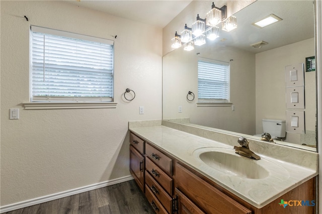 bathroom with plenty of natural light, wood-type flooring, toilet, and vanity