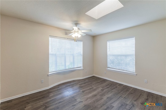 unfurnished room featuring dark wood-type flooring, a skylight, and ceiling fan