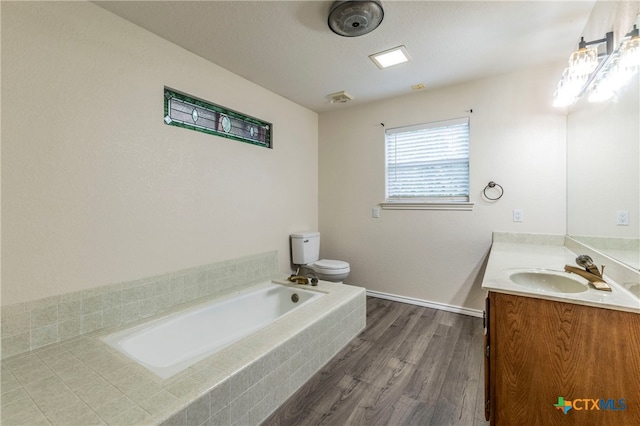 bathroom featuring tiled bath, wood-type flooring, toilet, and vanity