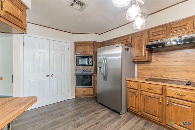 kitchen featuring black appliances, dark wood-type flooring, and crown molding