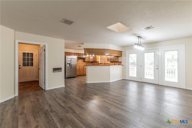 unfurnished living room featuring a textured ceiling, dark hardwood / wood-style floors, and a skylight