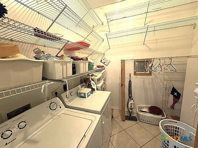 laundry area with washer and clothes dryer and light tile patterned floors