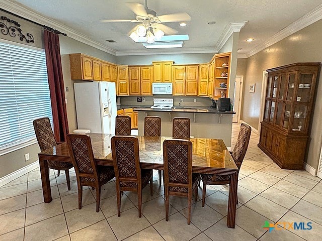 tiled dining area featuring ceiling fan and crown molding