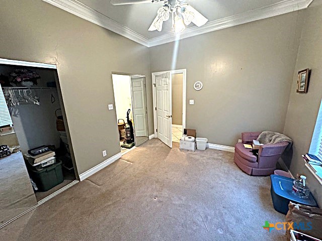 living area with carpet flooring, ceiling fan, and crown molding