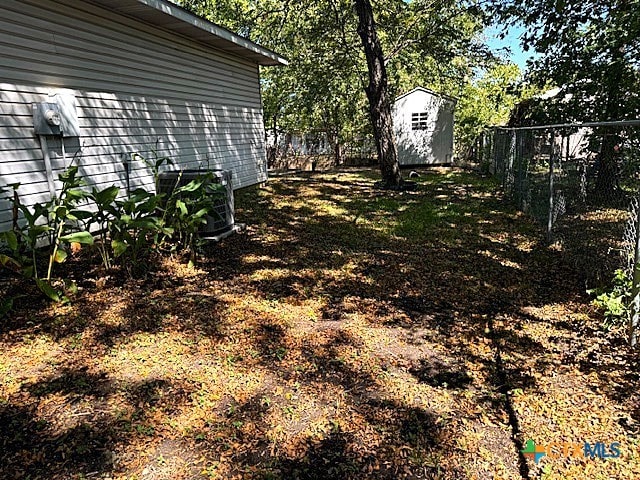 view of yard featuring central AC unit and a storage unit