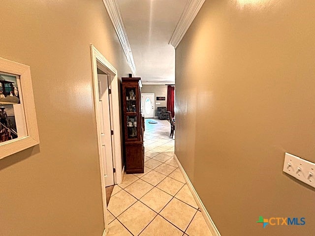 corridor with light tile patterned floors and crown molding