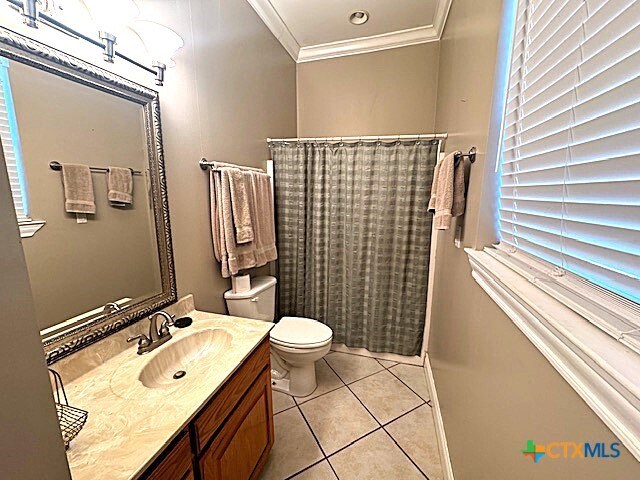 bathroom with walk in shower, ornamental molding, vanity, tile patterned flooring, and toilet