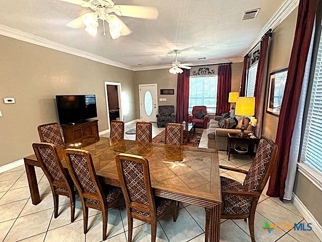 tiled dining room with ceiling fan and ornamental molding