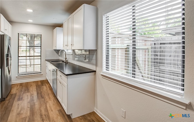 kitchen with stainless steel appliances, light hardwood / wood-style floors, white cabinetry, sink, and tasteful backsplash