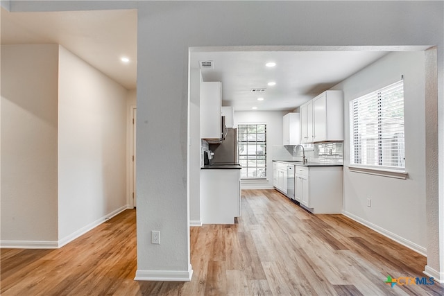 kitchen with light hardwood / wood-style floors, decorative backsplash, sink, white cabinetry, and appliances with stainless steel finishes