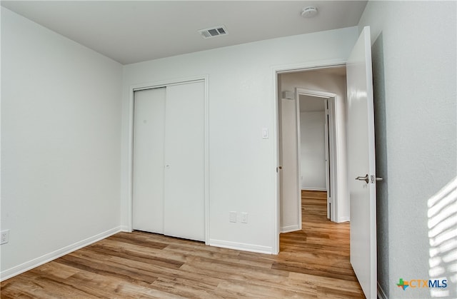 unfurnished bedroom with a closet and light hardwood / wood-style floors