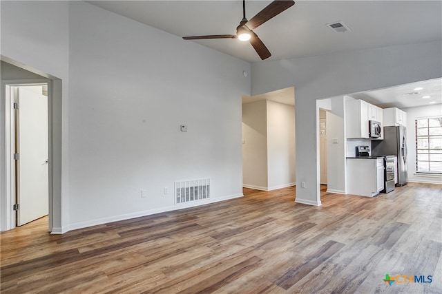 unfurnished living room with light wood-type flooring, ceiling fan, and high vaulted ceiling