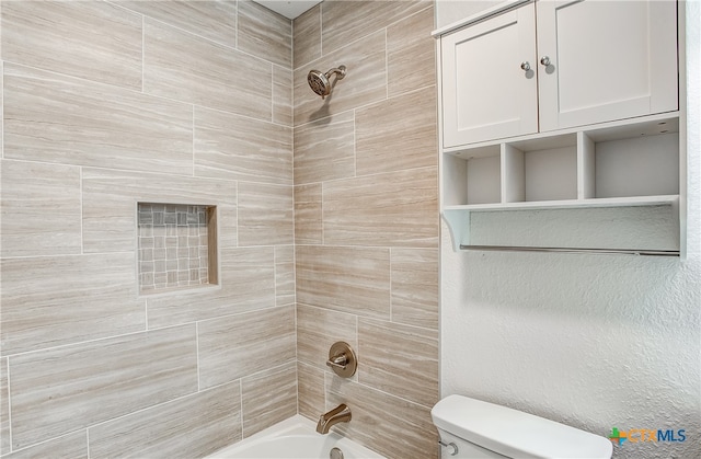 bathroom with tiled shower / bath combo and toilet