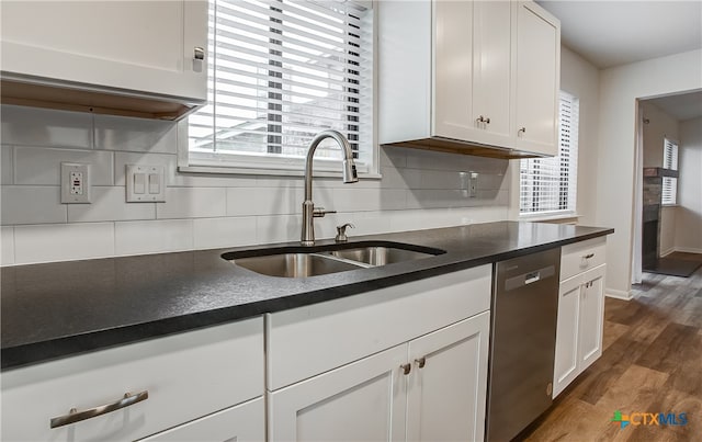 kitchen featuring dark wood-type flooring, stainless steel dishwasher, a wealth of natural light, and white cabinets