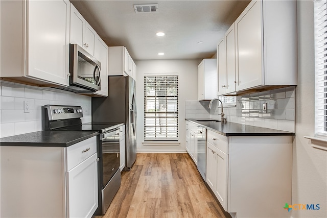 kitchen with white cabinets, light wood-type flooring, stainless steel appliances, and sink