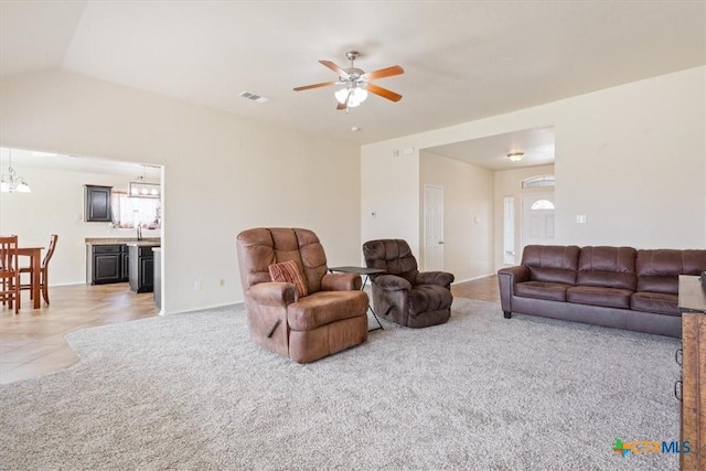 living room with lofted ceiling, light tile patterned flooring, light colored carpet, ceiling fan with notable chandelier, and visible vents