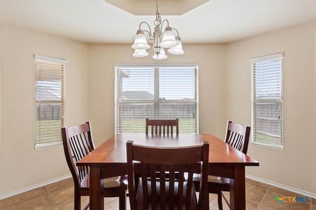 dining area featuring tile patterned flooring, a chandelier, and baseboards