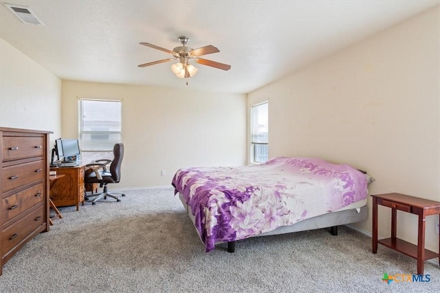 carpeted bedroom featuring a ceiling fan, visible vents, and baseboards