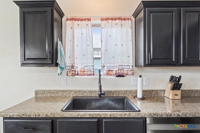 kitchen featuring dishwasher, a sink, and dark cabinets