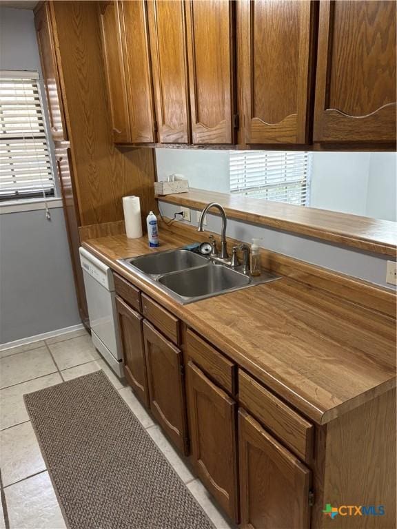 kitchen featuring dishwasher, sink, and light tile patterned floors