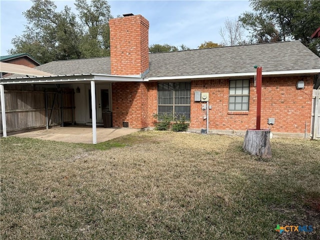 rear view of house with a shingled roof, a chimney, a lawn, and brick siding