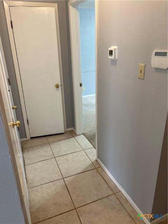 hallway featuring light tile patterned flooring and baseboards