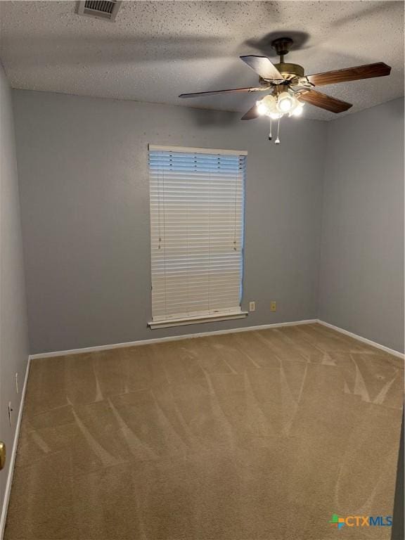 unfurnished room with a textured ceiling, carpet flooring, visible vents, and baseboards