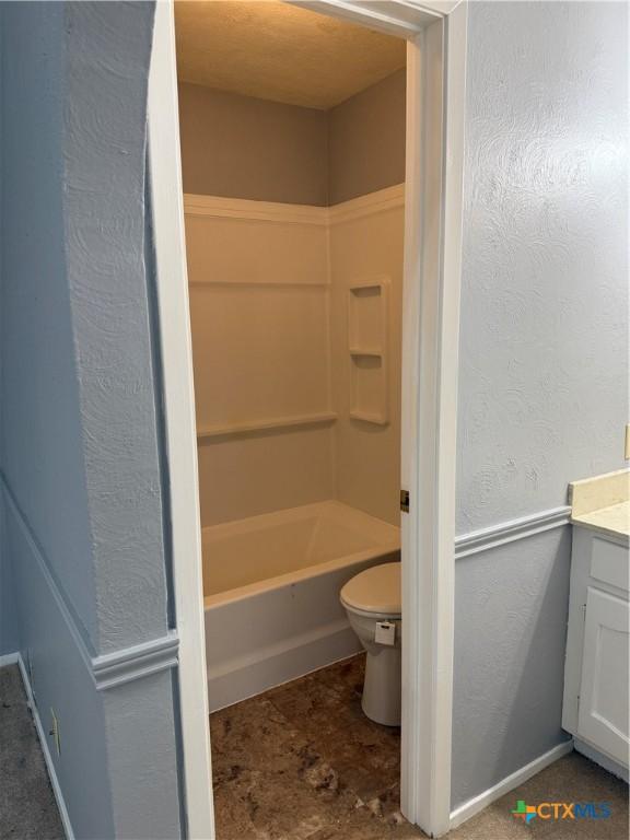 bathroom with toilet, a textured wall, and vanity