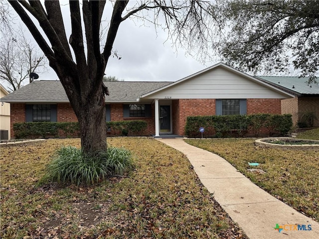 single story home with brick siding, a front yard, and central air condition unit