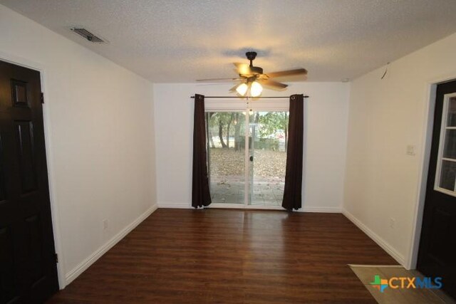 empty room featuring ceiling fan, dark wood-type flooring, and a textured ceiling