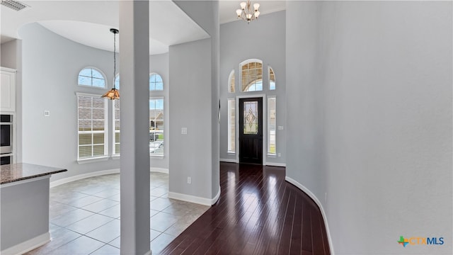 foyer featuring a towering ceiling, hardwood / wood-style floors, a wealth of natural light, and a chandelier