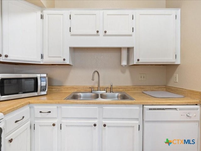 kitchen featuring white dishwasher, sink, and white cabinetry