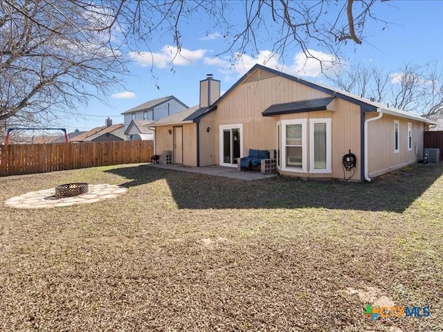 back of house featuring central AC unit, a patio area, a fire pit, and a lawn