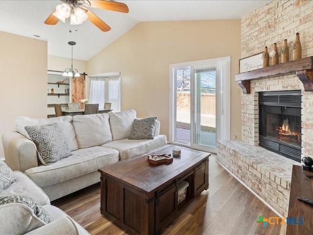 living room with ceiling fan, a brick fireplace, lofted ceiling, and dark hardwood / wood-style flooring