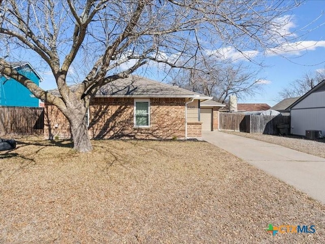 ranch-style house with a garage, cooling unit, and a front yard