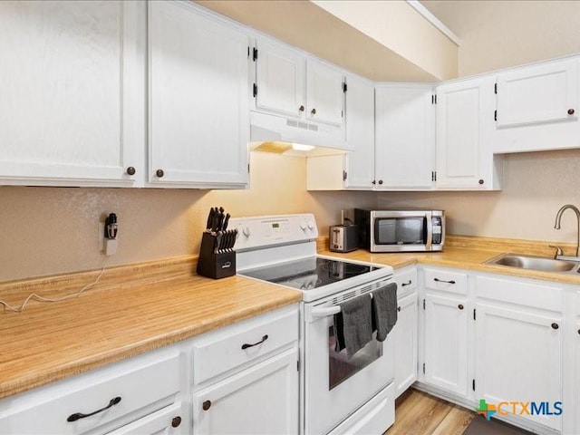 kitchen featuring white electric stove, sink, and white cabinets