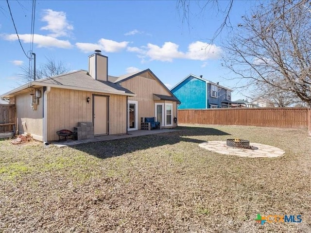 back of property featuring a fire pit and a lawn