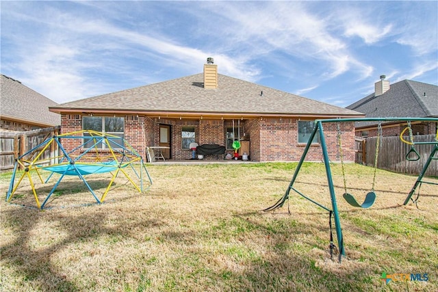 rear view of property featuring brick siding, a chimney, a fenced backyard, a yard, and a patio