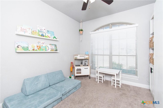 living area featuring baseboards, plenty of natural light, carpet, and ceiling fan