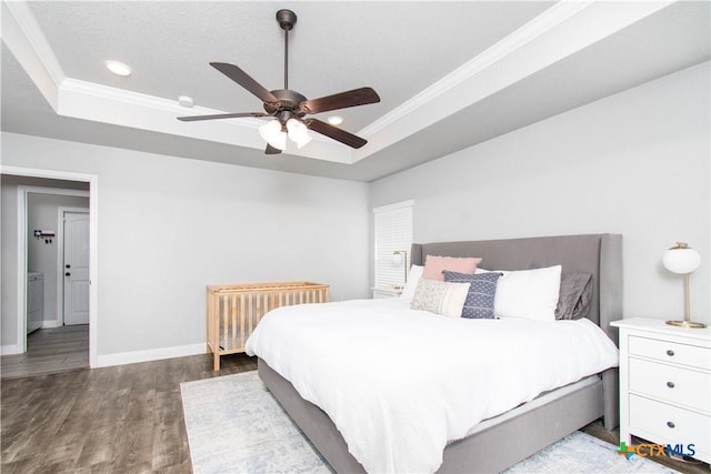 bedroom with a tray ceiling, baseboards, wood finished floors, and ornamental molding