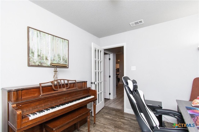 office area featuring visible vents, a textured ceiling, baseboards, and wood finished floors