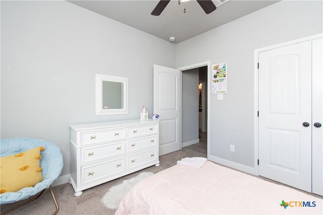 bedroom with a closet, baseboards, light colored carpet, and ceiling fan