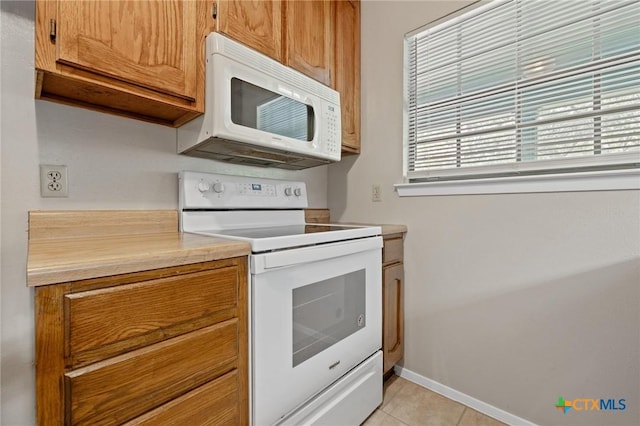 2209 Winchester Dr, Temple, TX 76502 - kitchen featuring white appliances, brown cabinetry, light countertops, and light tile patterned floors