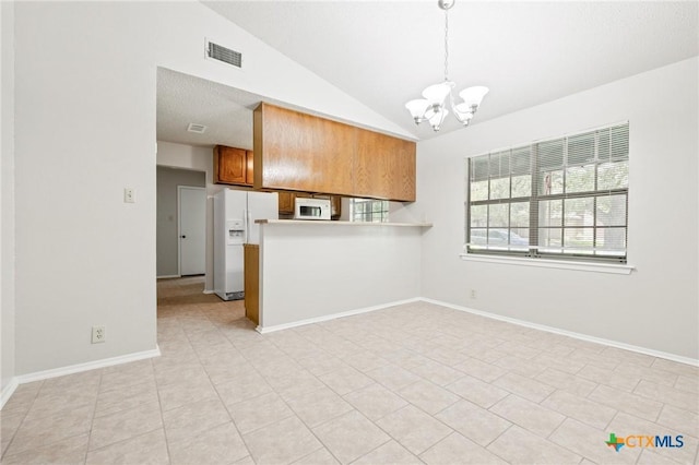 2209 Winchester Dr, Temple, TX 76502 - kitchen featuring white appliances, brown cabinetry, a chandelier, vaulted ceiling, and a peninsula