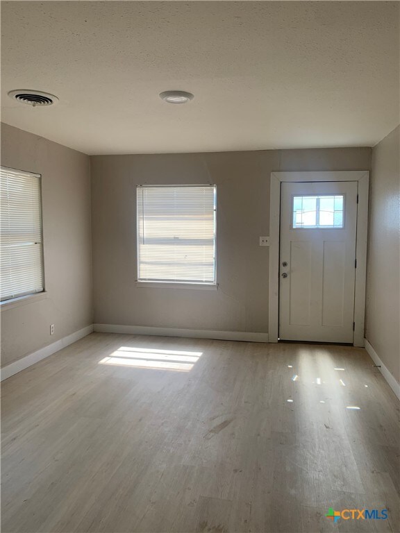 foyer entrance with a textured ceiling and light hardwood / wood-style floors