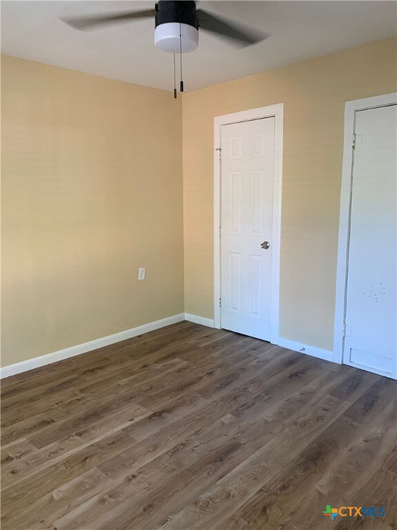 unfurnished bedroom with dark wood-type flooring and ceiling fan