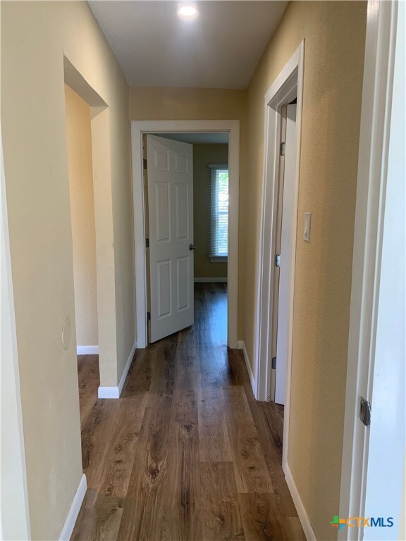 corridor with dark hardwood / wood-style flooring